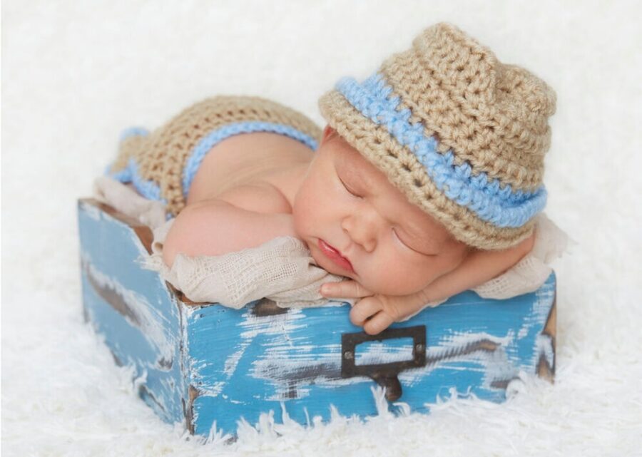 Newborn Photography in white knit cap lying on blue and white textile